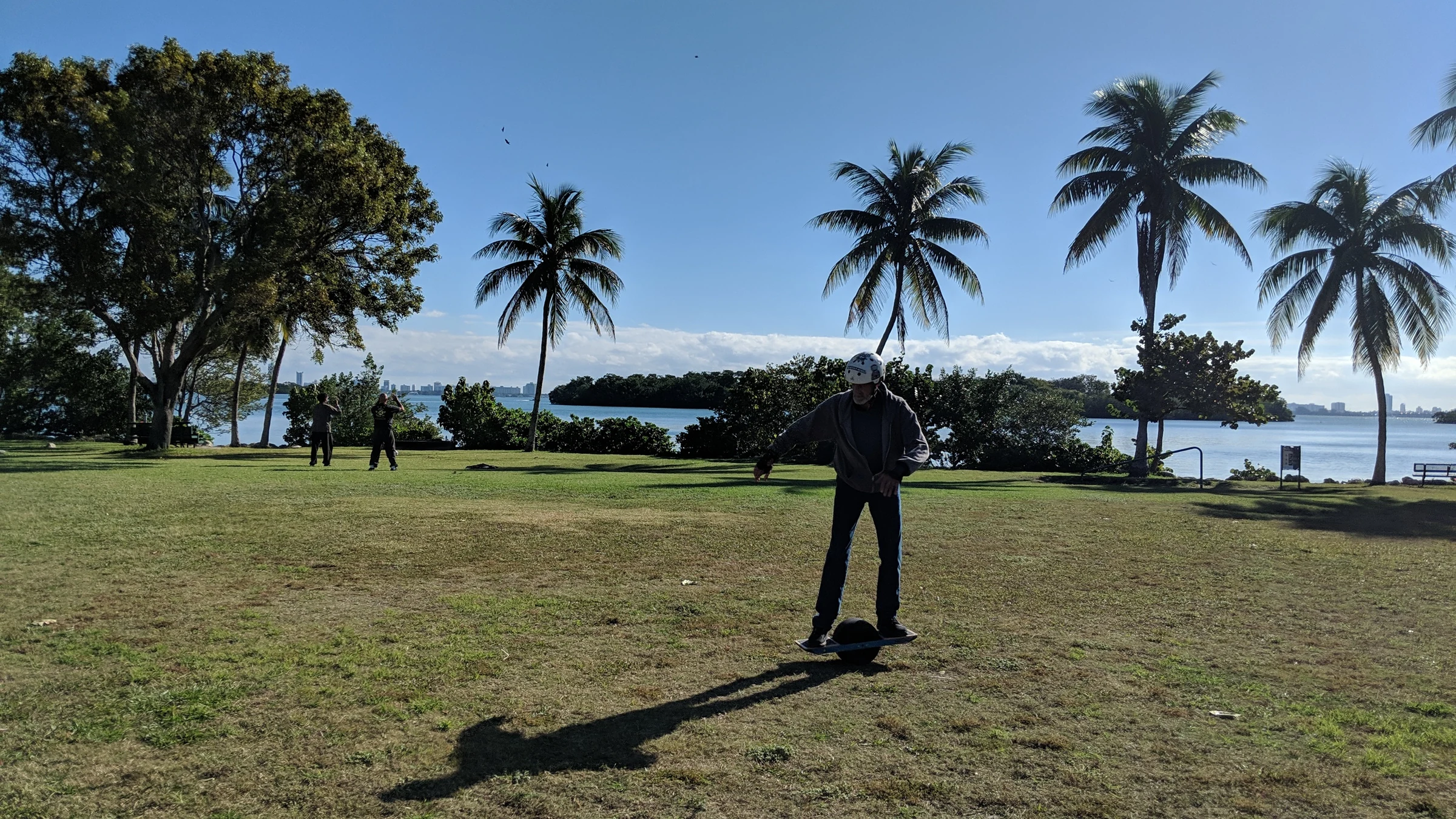 Gary Boehne riding his Onewheel across grass beside the water in Miami.