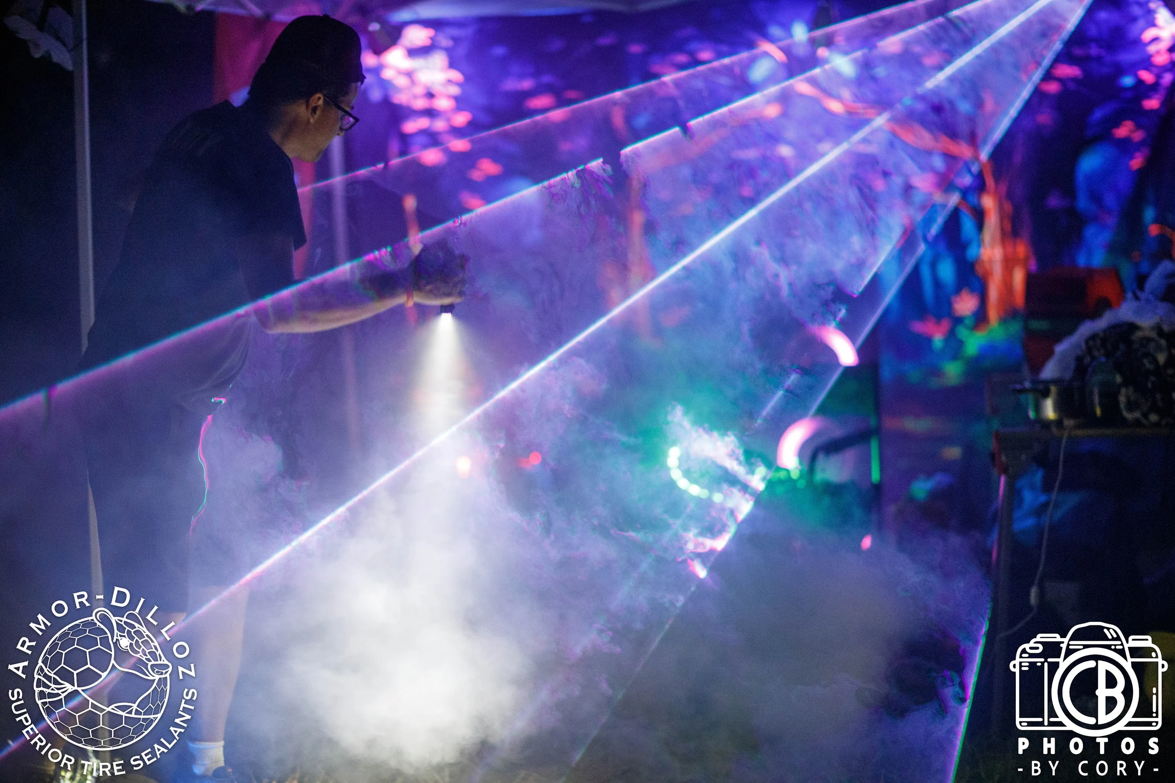 A festivalgoer surrounded by blue and purple light and haze at night.