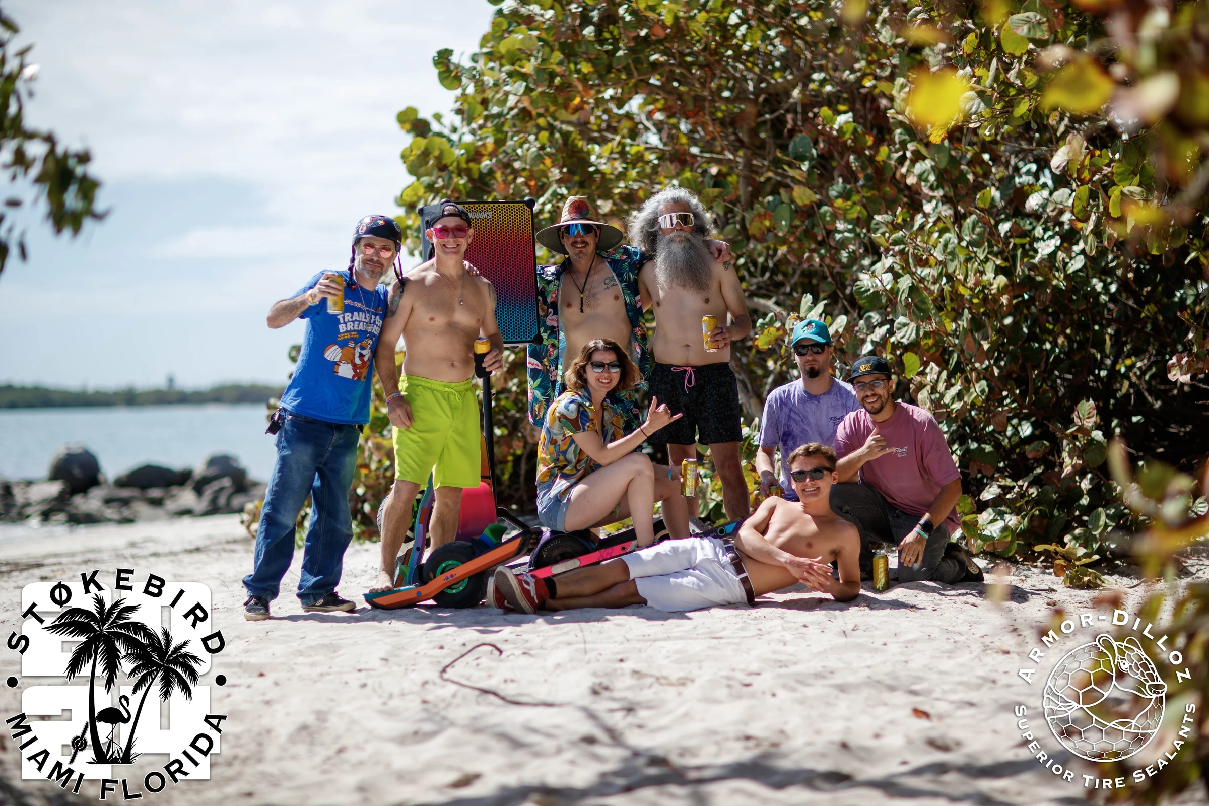 A group of riders with colorful Onewheels gathered by the water.